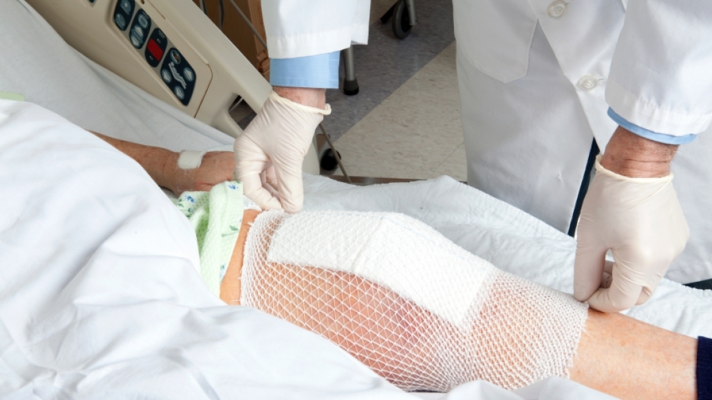 Doctor applying a bandage to a man's knee