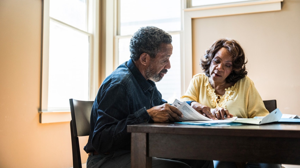 couple sitting at table with newspaper 