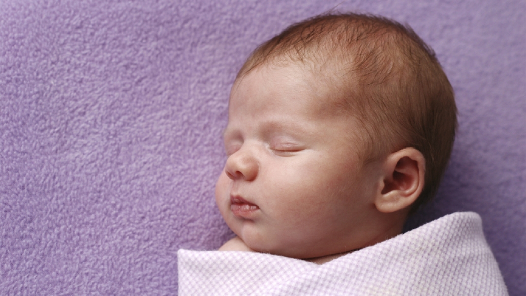 baby swaddled in pink cloth laying