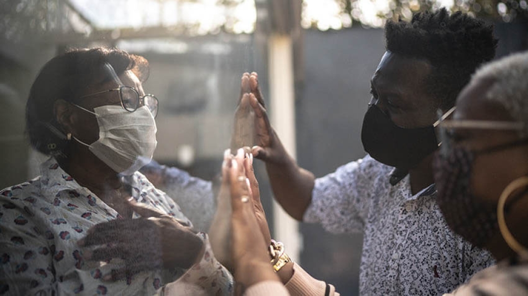 Visiting quarantined mother communicating through a glass window