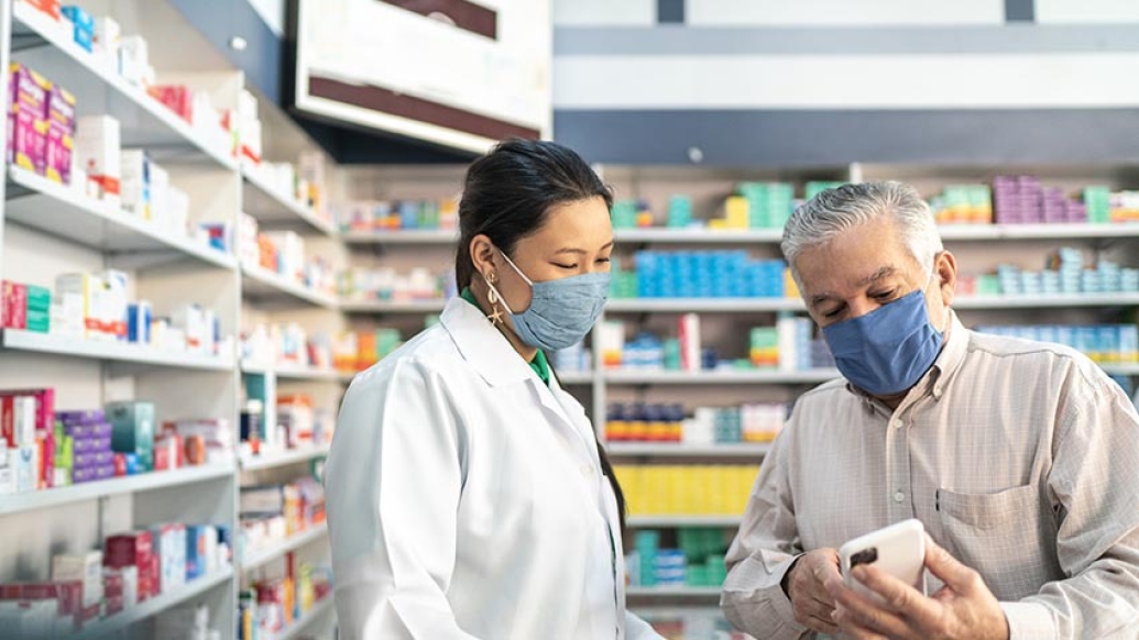 doctor helping gentleman looking at pills in pharmacy