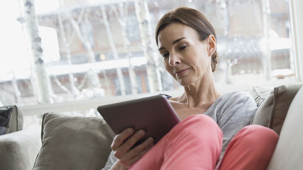 Woman sitting on a sofa reading from an ipad
