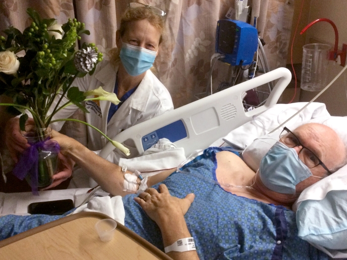Doctor with mask on standing by patient in hosptial bed
