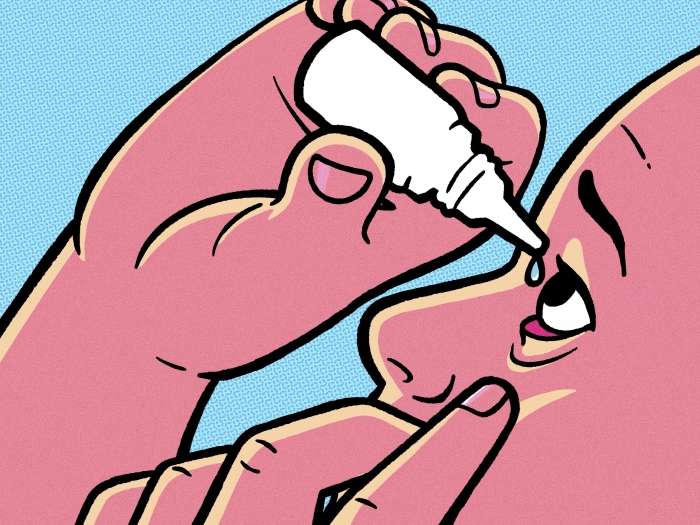 Hand putting eye drops in eye