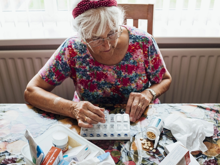 older woman at table with medicine pills in front of her