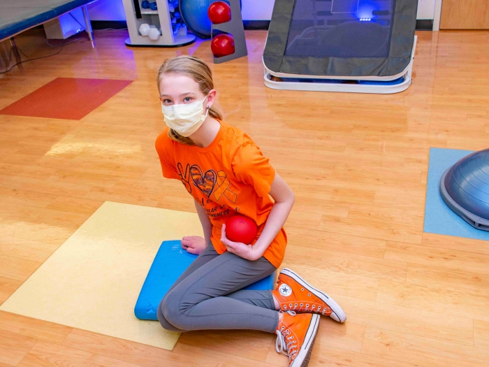 little girl sitting in gym with orange shirt and orange converses 