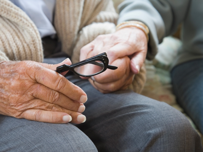 older woman holding glasses in lap