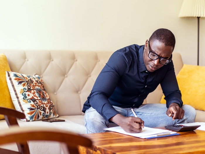 man at table writing down in living room