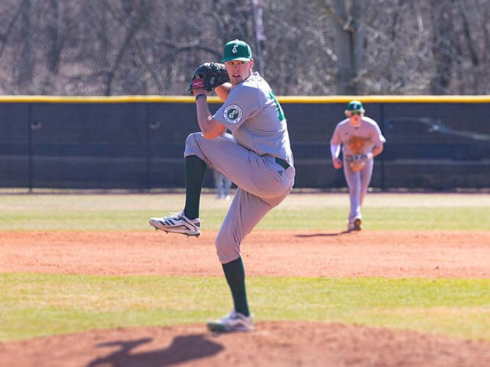 Baseball player pitching ball on baseball field with other baseball players