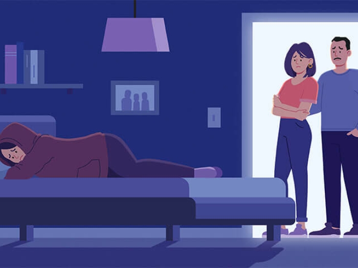 Parents standing at doorway near depressed teenagers bed