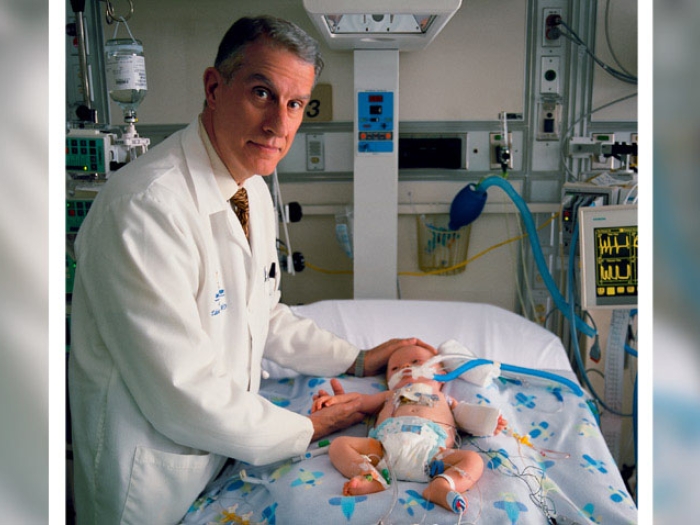 Doctor smiling by bed near baby with tubes