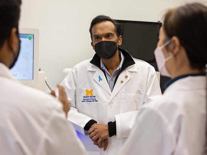 Doctors talking in office wearing white lab coats and masks. 
