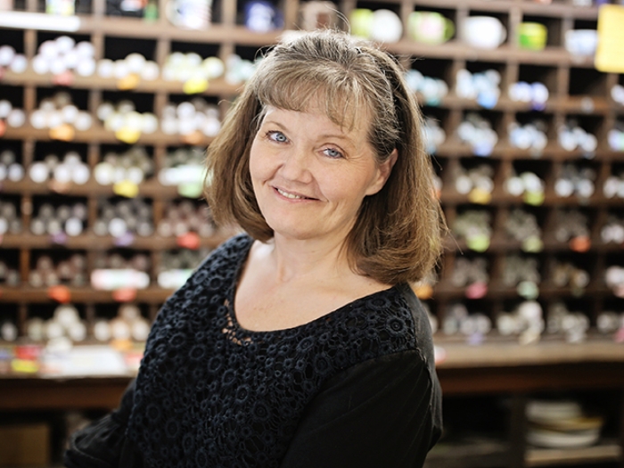 Traci Lawson shelves of art supplies behind her
