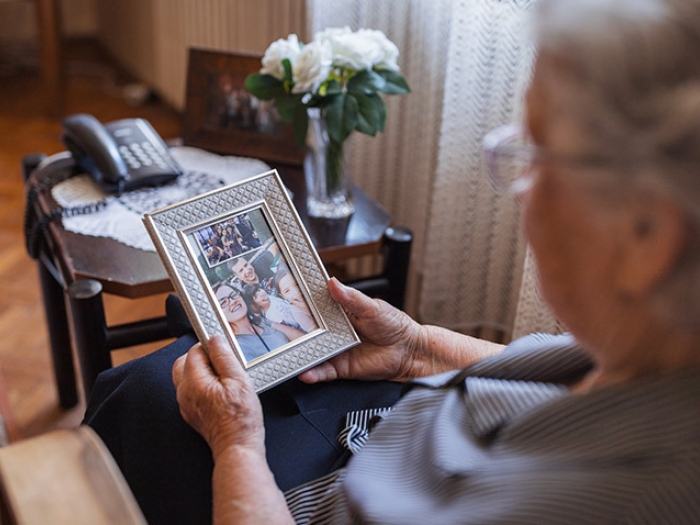 elderly woman family portrait frame looking at in hand