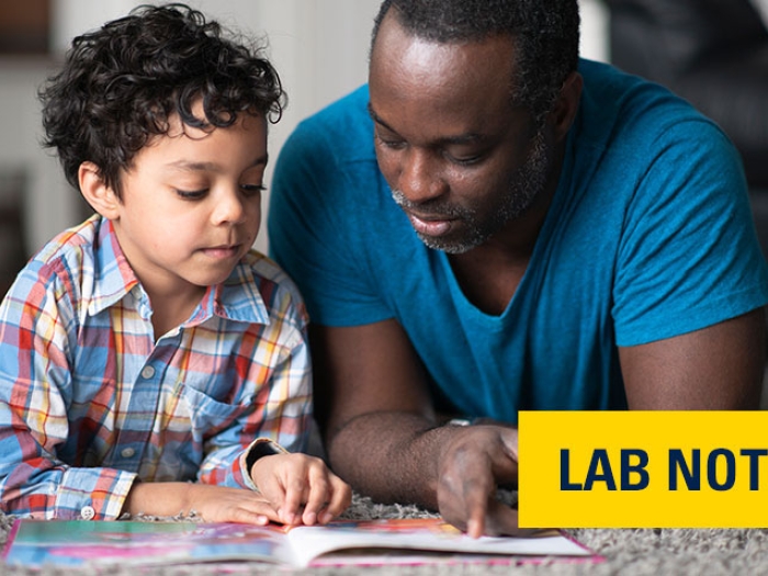 Father and son laying on floor reading a book together