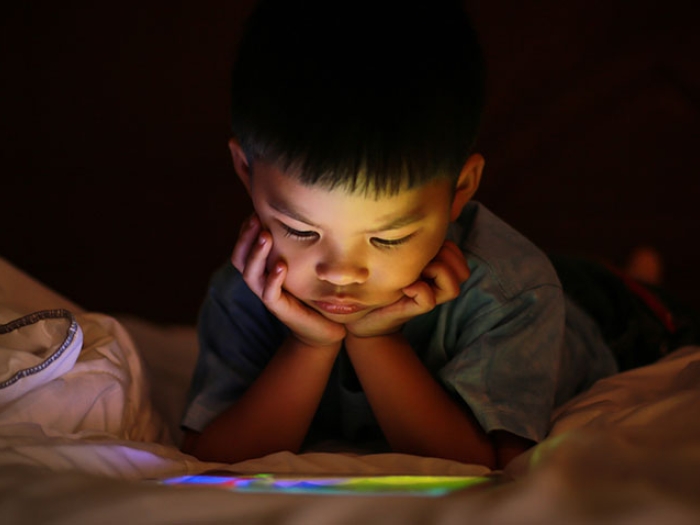 Child with ipad in bed