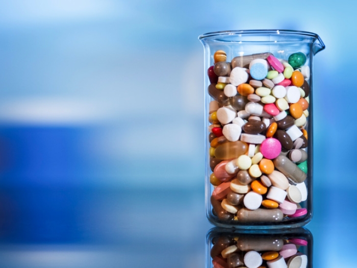 glass beaker filled with colorful pills