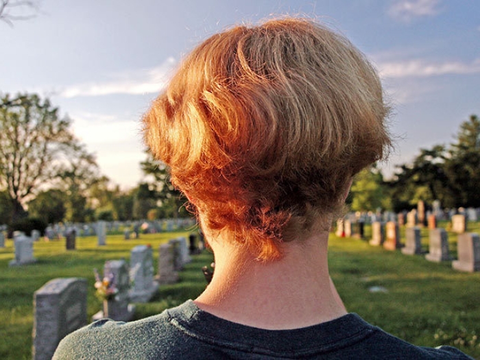 head shoulders view from back in front of graveyard headstones with sun and blue sky