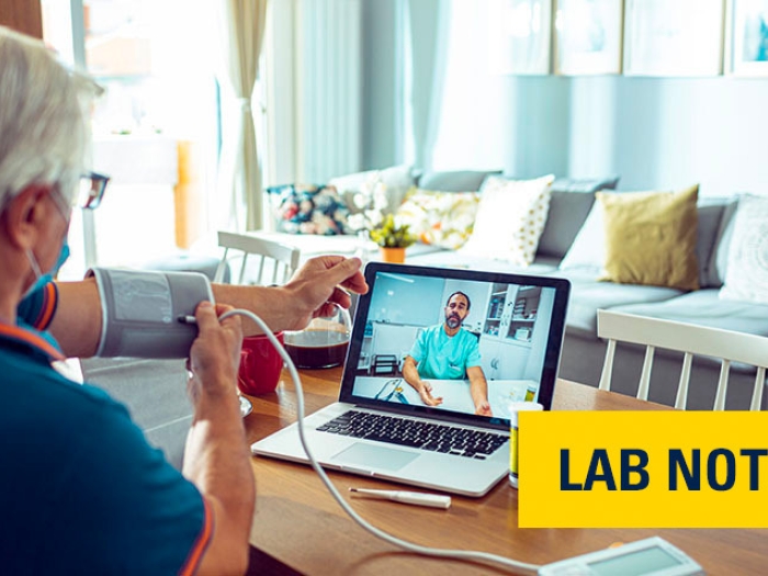 man with blood pressure cuff talking to doctor on ipad