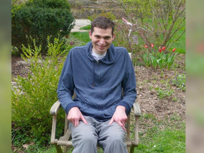 Man sitting in wheel chair by garden of flowers smiling