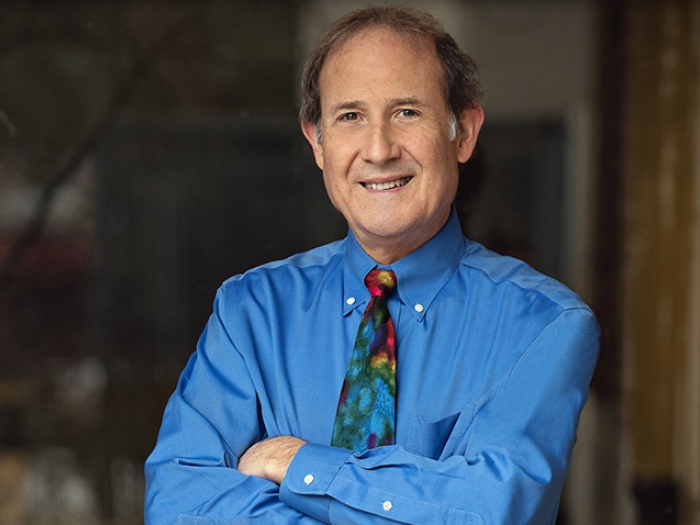 man smiling in rainbow tie in blue shirt