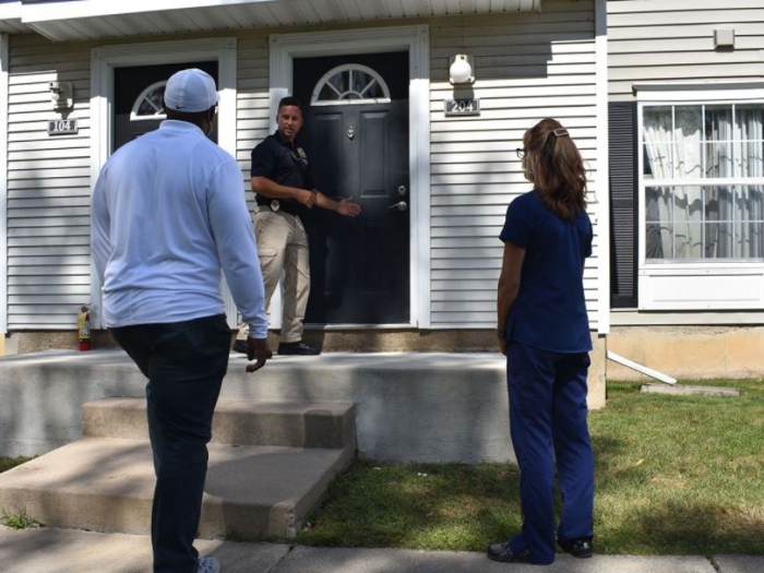 man at door and two people watching outside with masks on