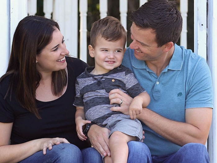 Mother and father sitting on porch with son smiling