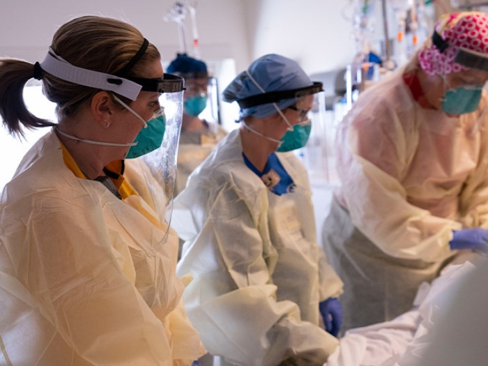 nurse team by bedside with covid patient