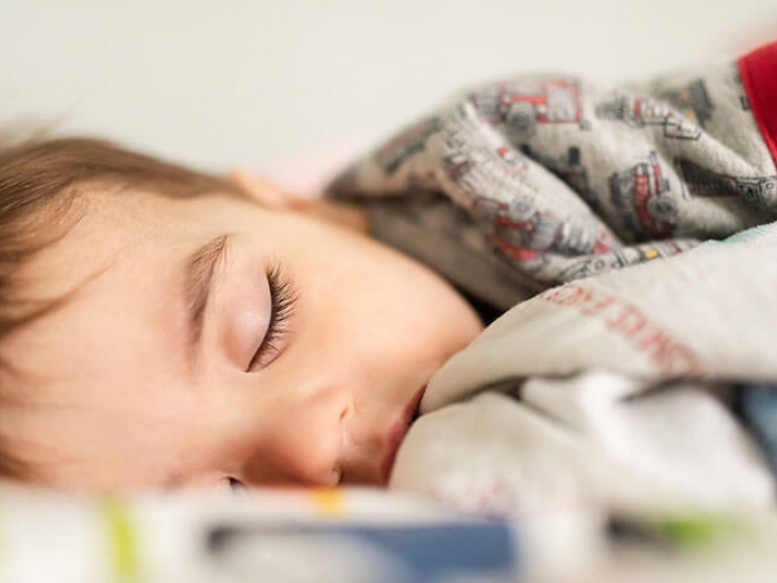 Sleeping child laying in bed with blankets