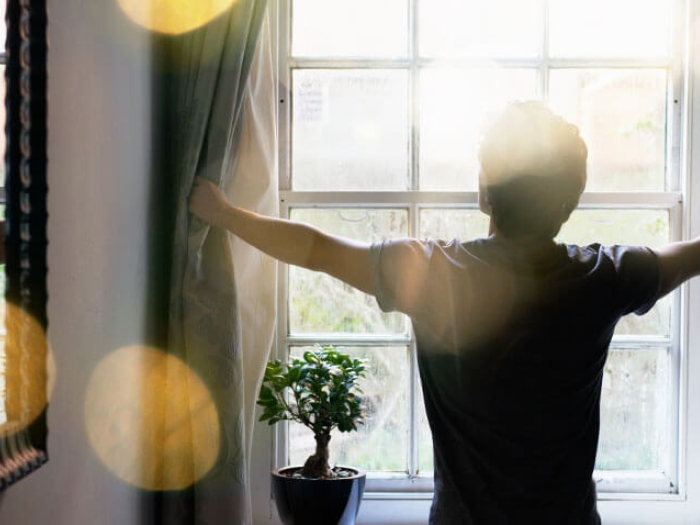 Child opening curtain and sun shining through