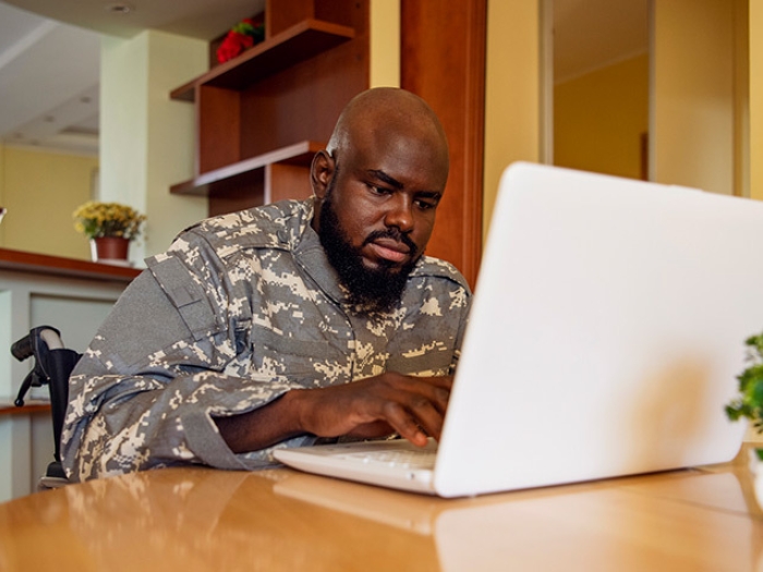 veteran in wheelchair on laptop in kitchen