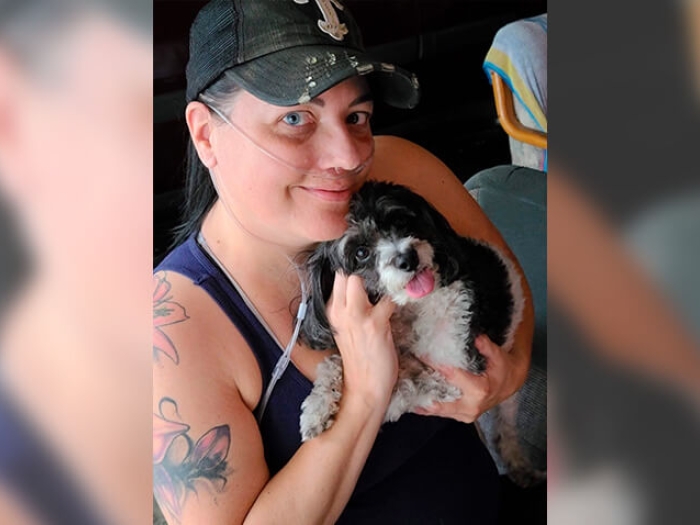 Women in hat holding dog while on oxygen tube