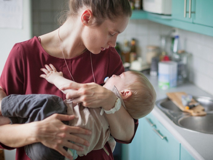 woman holding sleeping baby kitchen