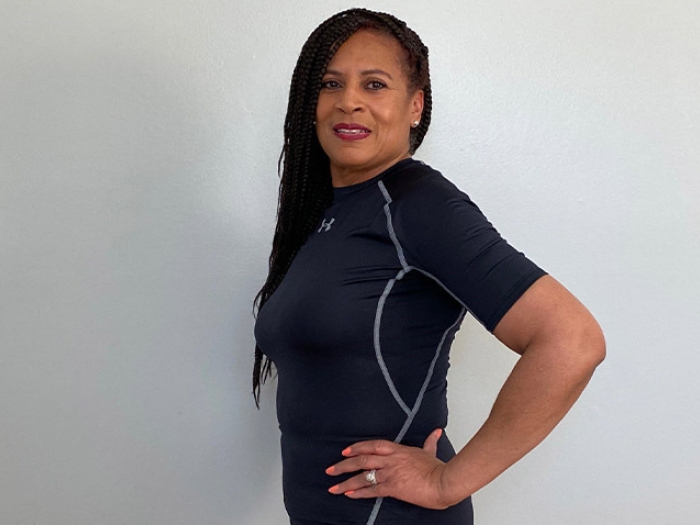woman standing side profile in black shirt in front of white wall