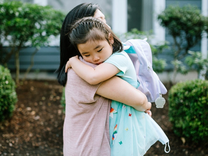 young girl hugging her mother backpack