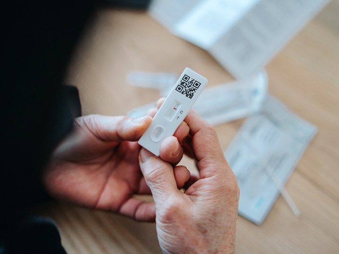 adult holding covid test low wrappings in background