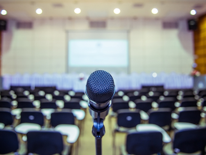 black mic stand in front of black chairs in an auditorium 