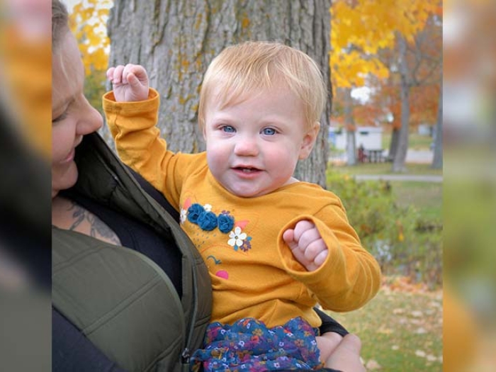 child in moms arms with yellow shirt on 