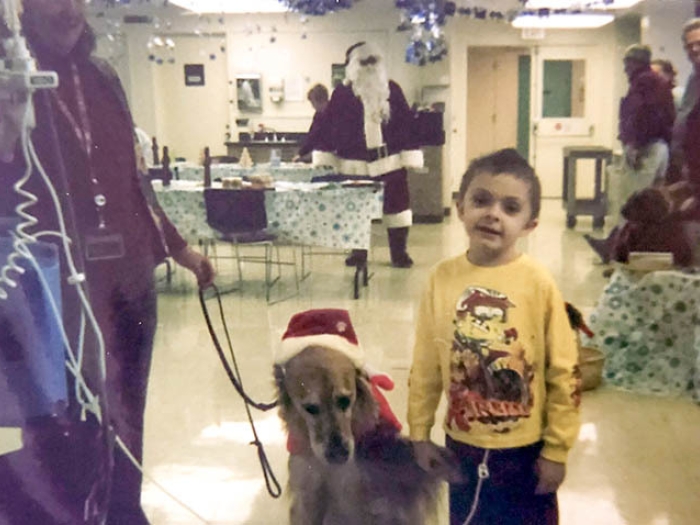 child standing with dog in hospital yellow shirt
