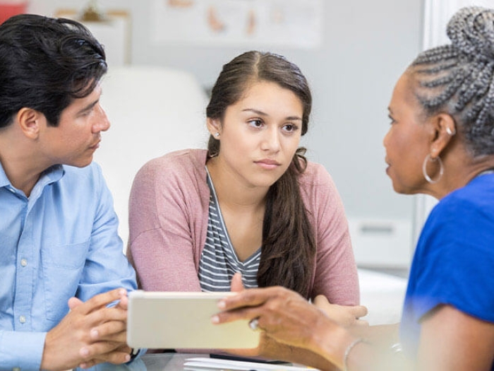 Father and daughter sitting in office talking to doctor