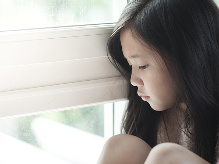 Sad young girl looking out a window