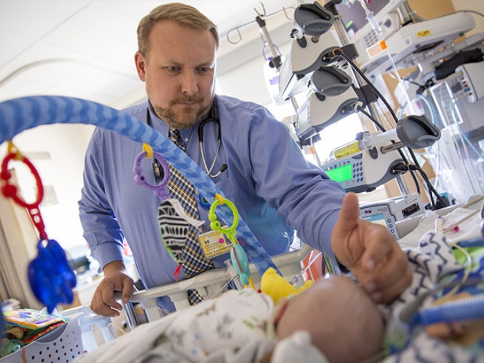 Provider standing over baby with pacifier in hospital