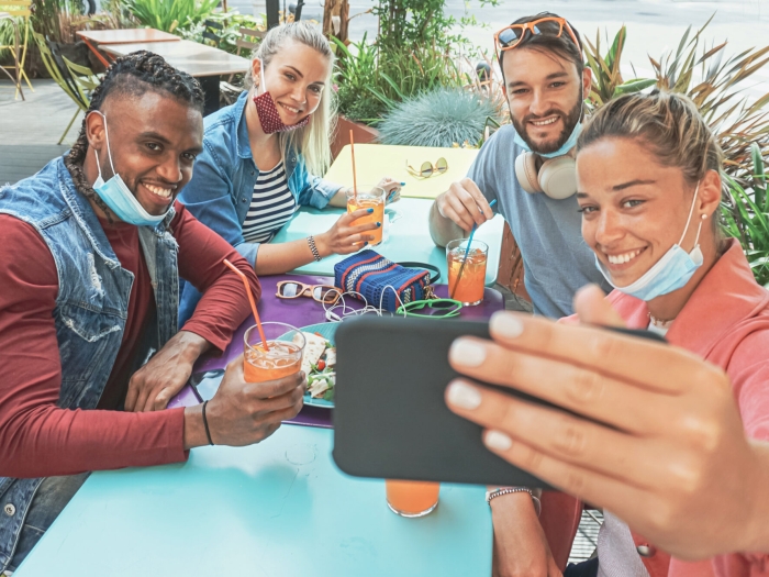 people sitting together with masks pulled down taking a selfie at a picnic table