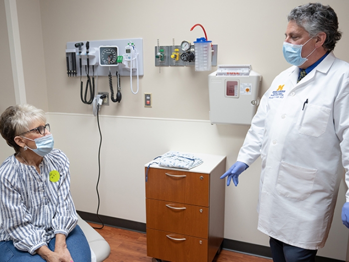 patient with mask on looking at doctor in exam room with mask on standing