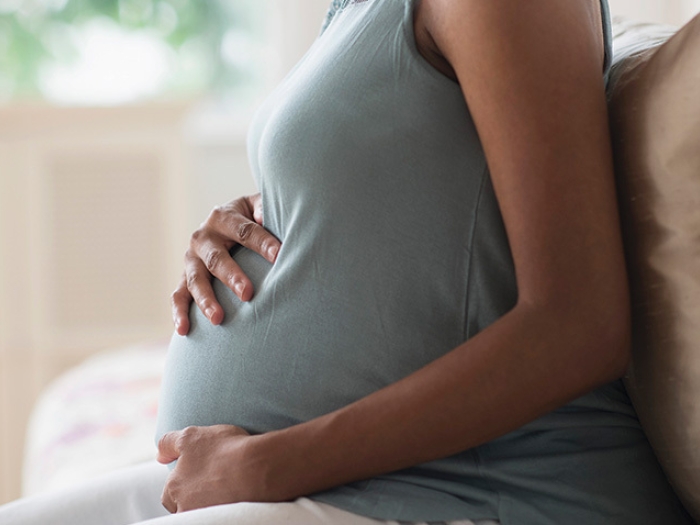 person pregnant holding stomach green shirt sleeveless