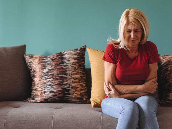 Woman sitting on couch with stomach pain