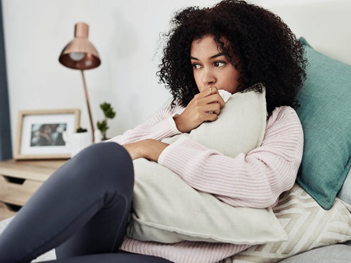 young woman lying down on bed hugging pillow