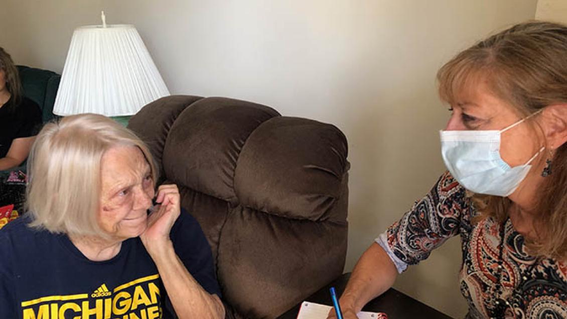Elderly woman smiling at woman wearing mask.
